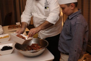 A chef from Hive Living Room + Bar at the Renaissance Westchester
Hotel hosts a cooking demonstration for attendees with his son acting
as sous chef. Photo/Andrew Dapolite