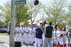 Dom Cecere Jr., right, and Eastcehster coach Jesse Waters officials unveil the new street sign renaming a portion of Stewart Place “Dom Cecere Way.” The May 7 ceremony was a testament to legendary coach Dom Cecere’s impact on the Eastchester community.